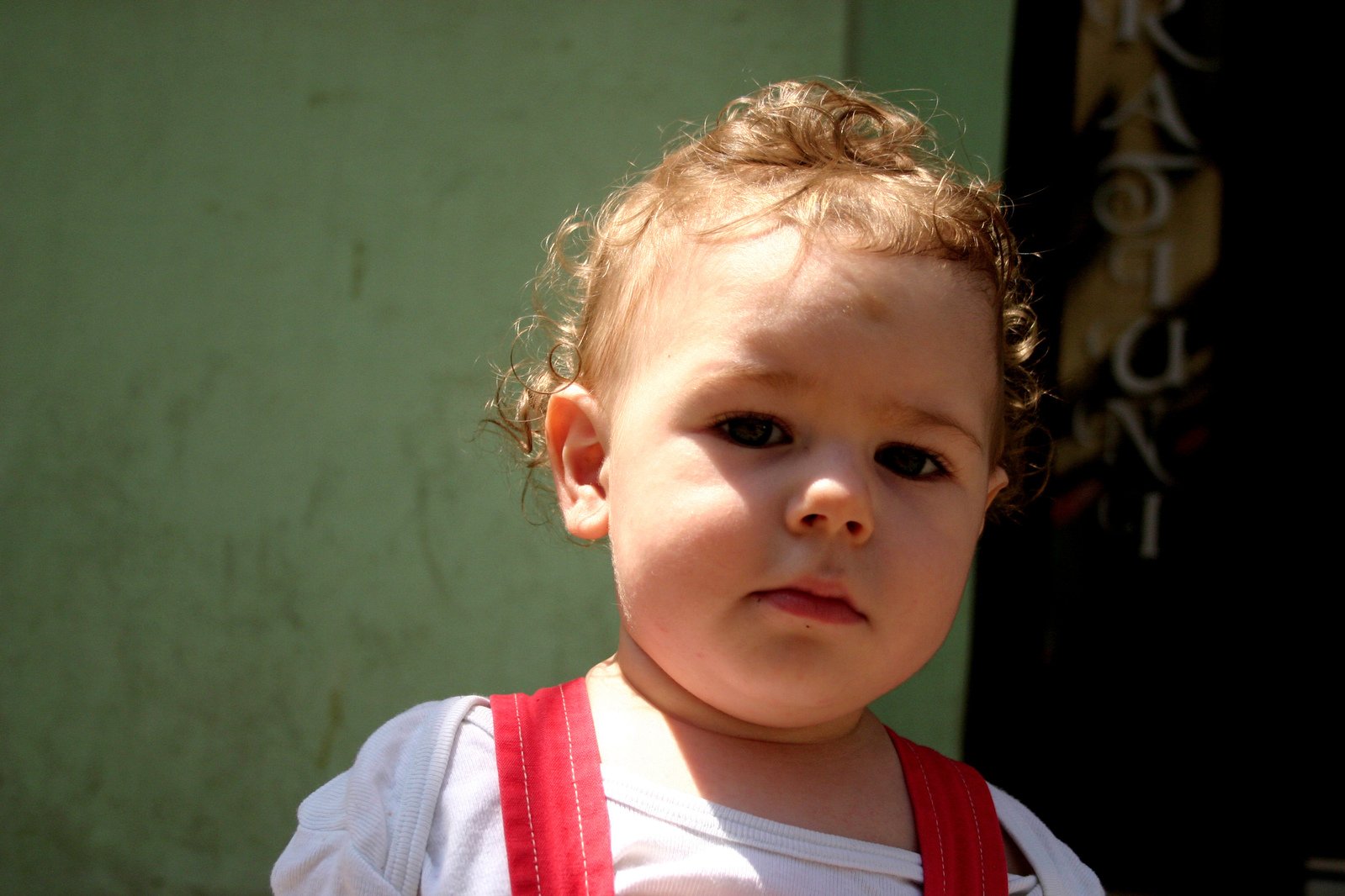 a little child wearing a red bib looking down