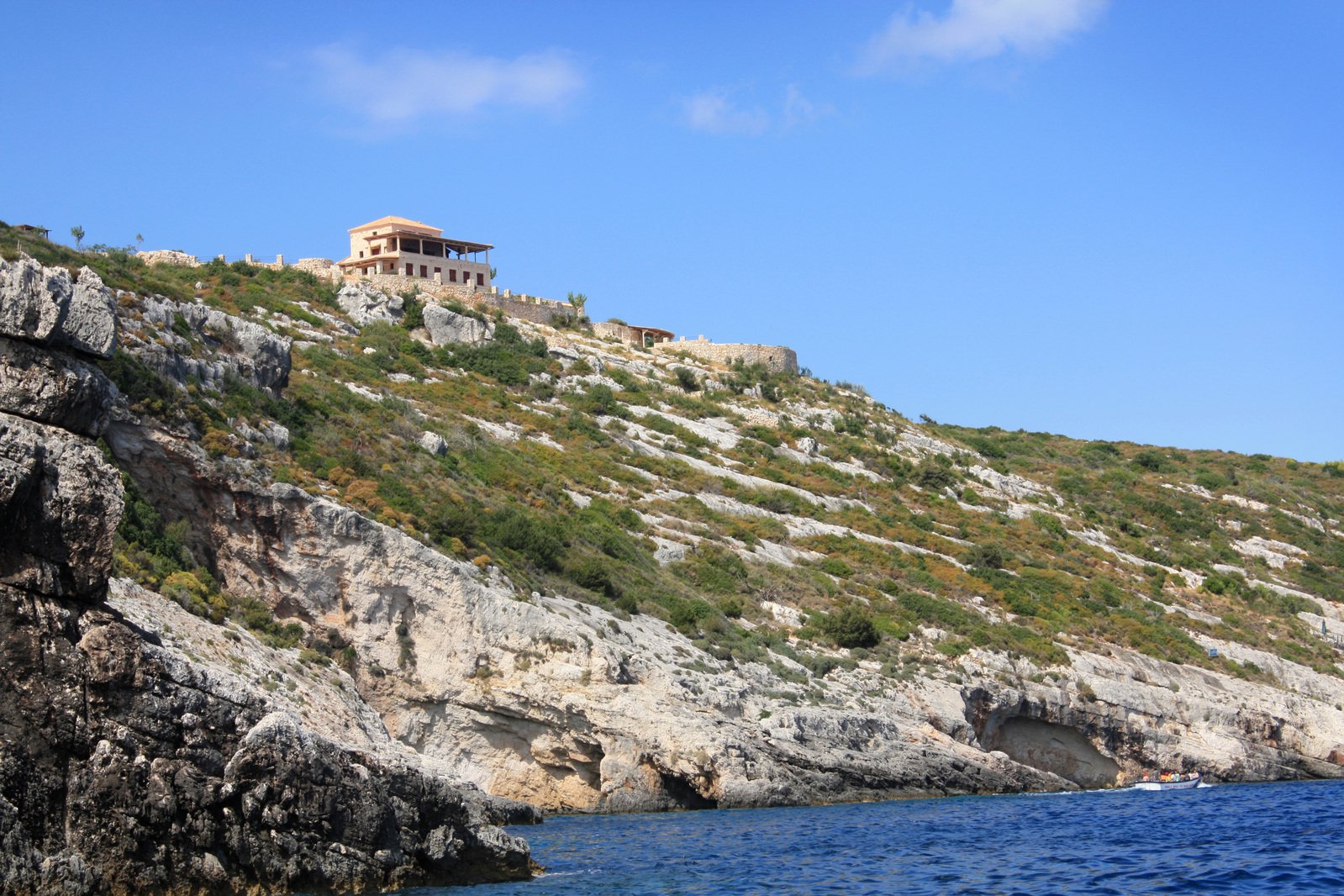 a cliff side house overlooking the blue water