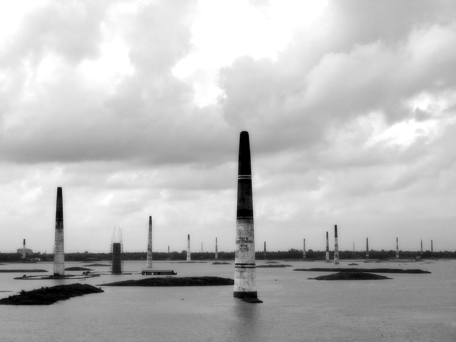 a black and white image of some poles in the water