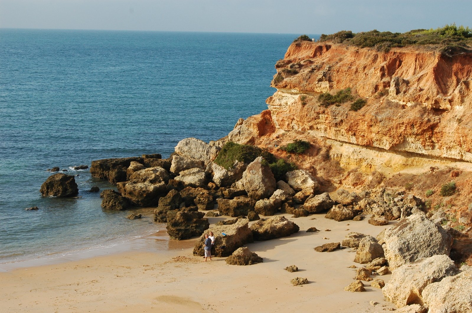 a sandy beach next to some cliff on top of it