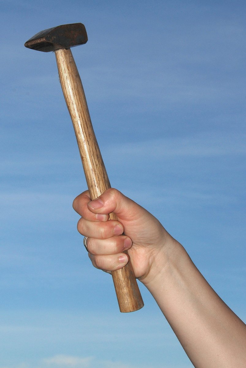 a close up of a person holding a wooden hammer