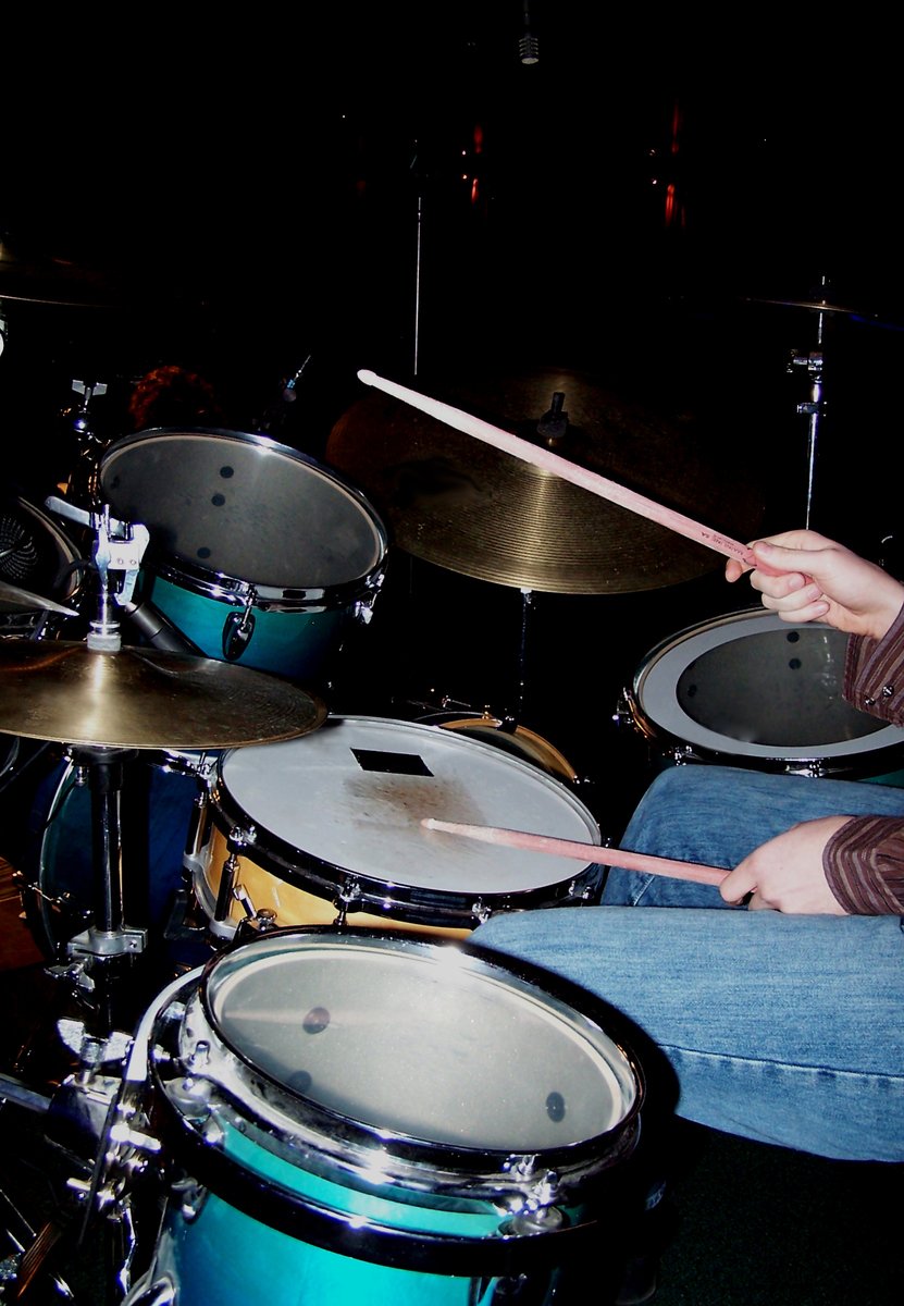 man in striped shirt playing drums on stage