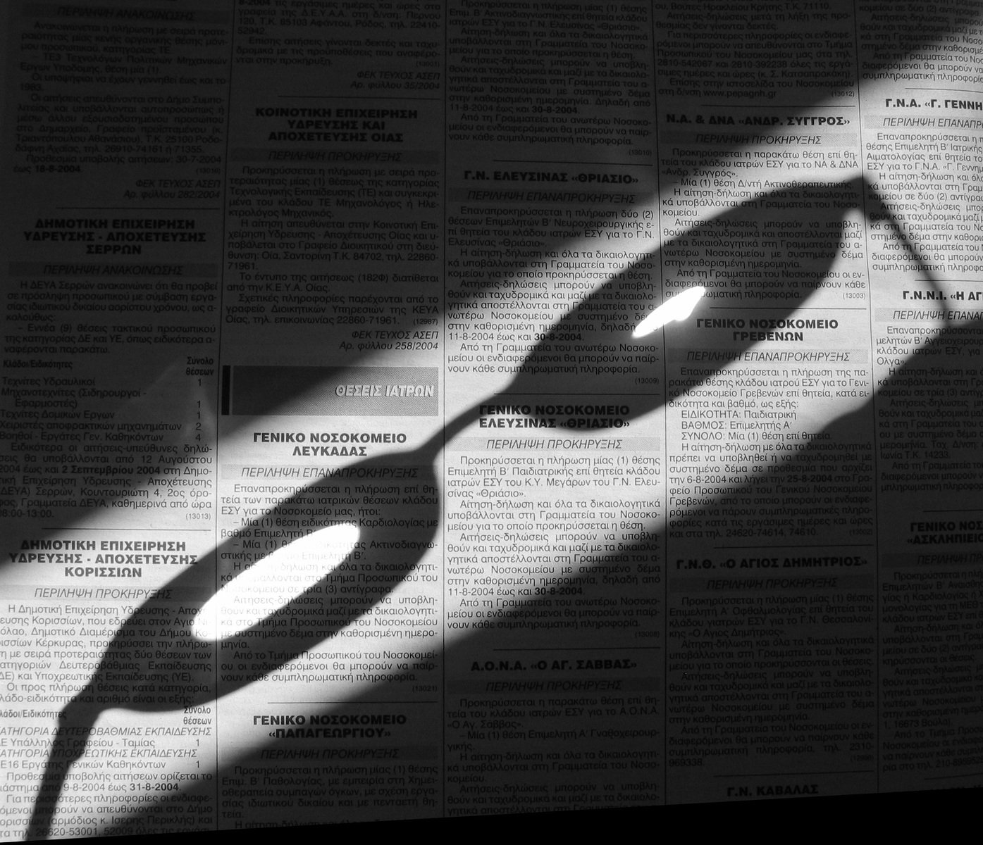 a close up of the shadow of a man's hand on news paper
