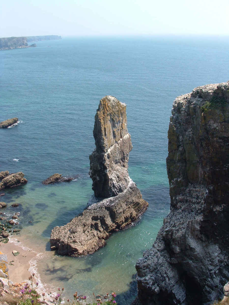 a group of cliffs sitting in the water near a shore