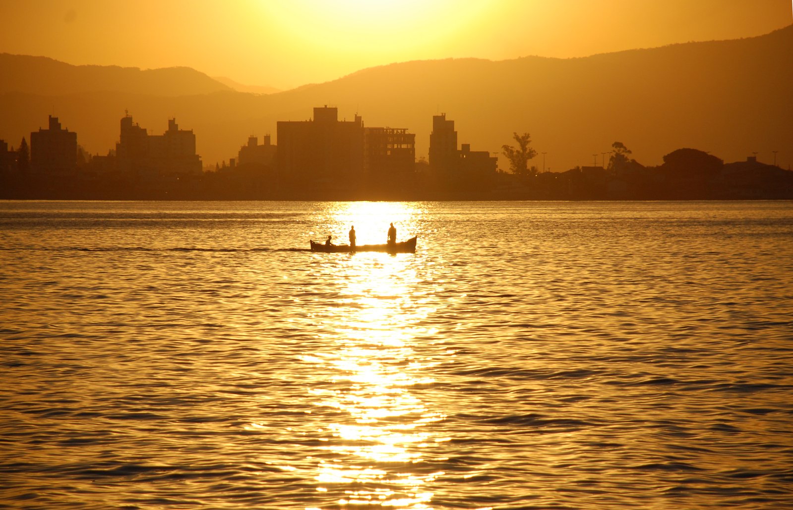 two people paddling on a canoe in the water at sunset