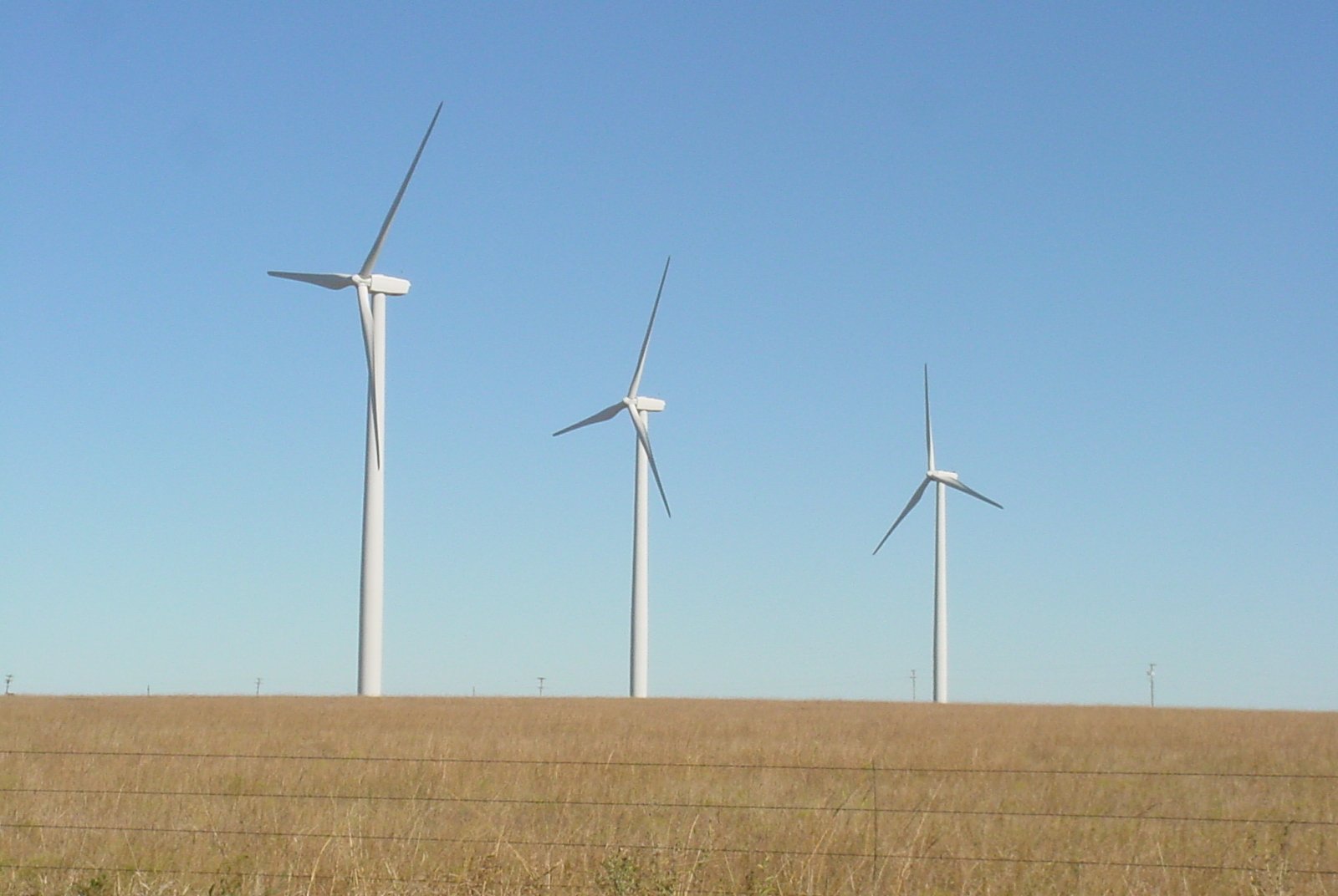 three wind mills on the prairie on a clear day