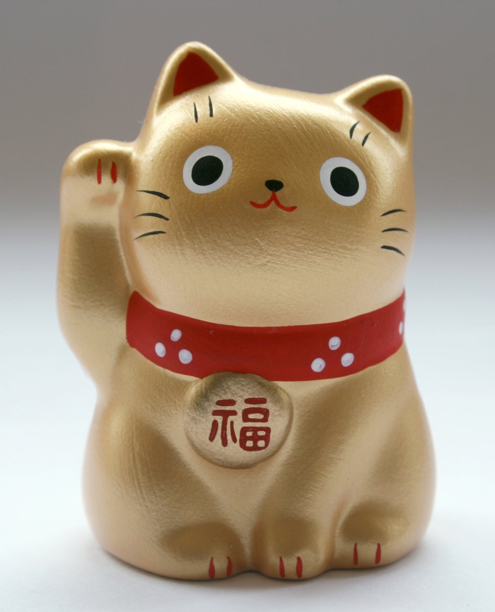 a small gold cat figurine holding onto a red and white ribbon