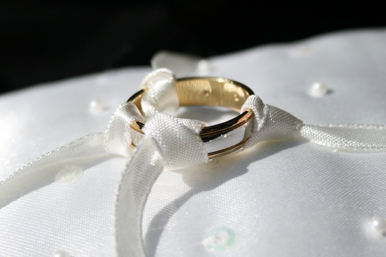 two wedding rings with bows are on top of a white fabric