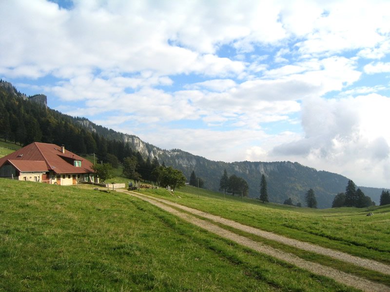 a house is shown on a hillside with mountains in the background