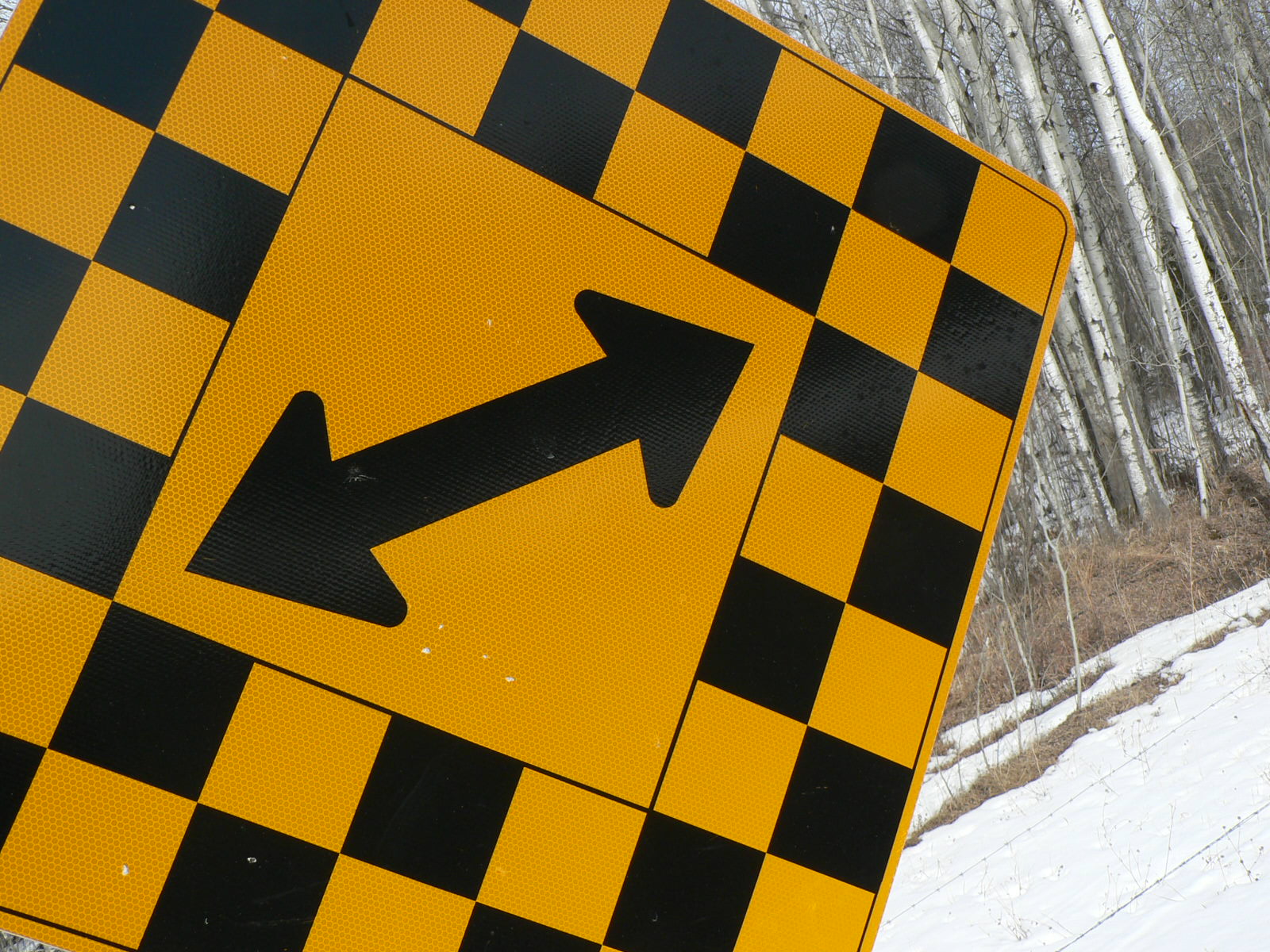 there is a yellow and black road sign in the snow