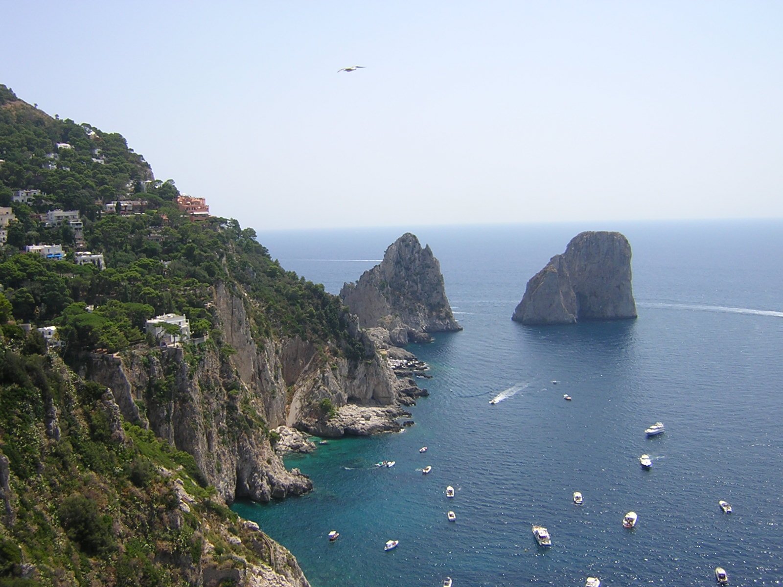 boats floating around on the ocean near some mountains