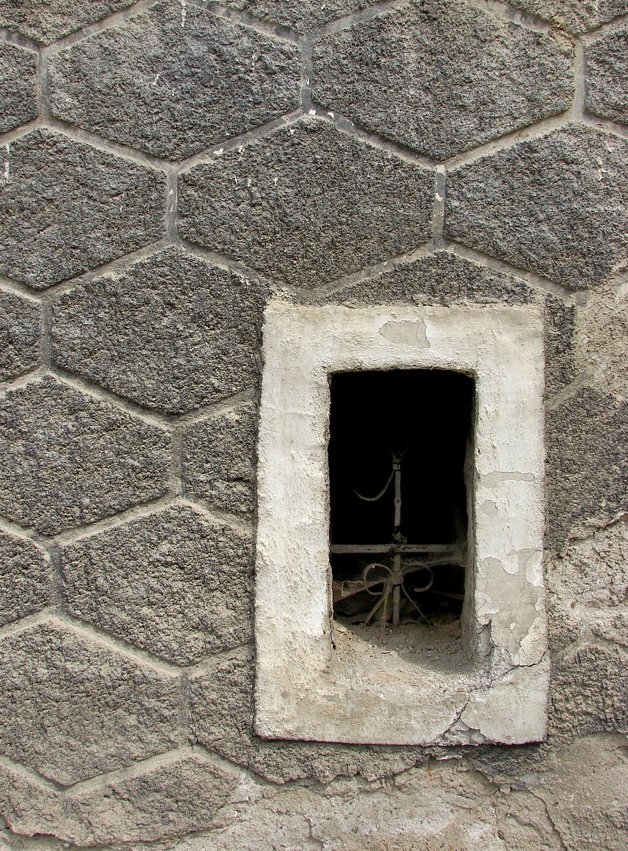 a grates is placed at the bottom of an open hole in a stone wall