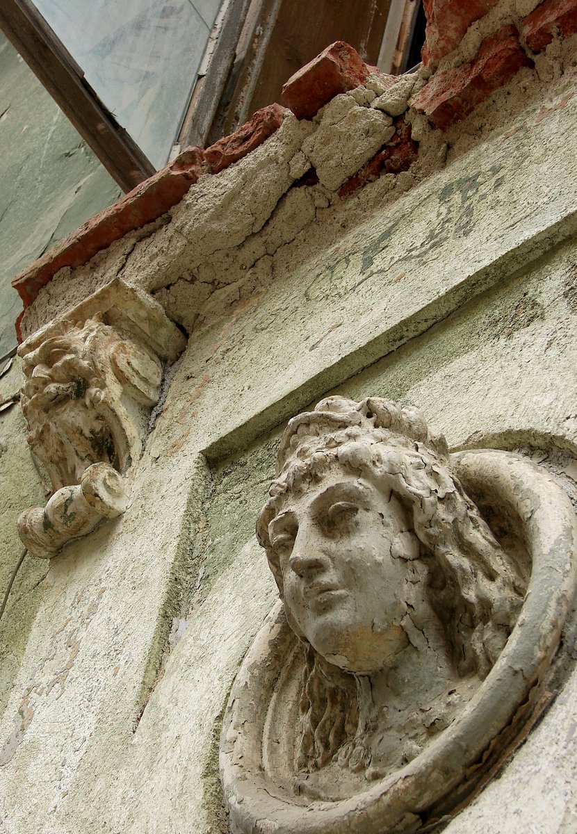 some statues of head on the side of an old building