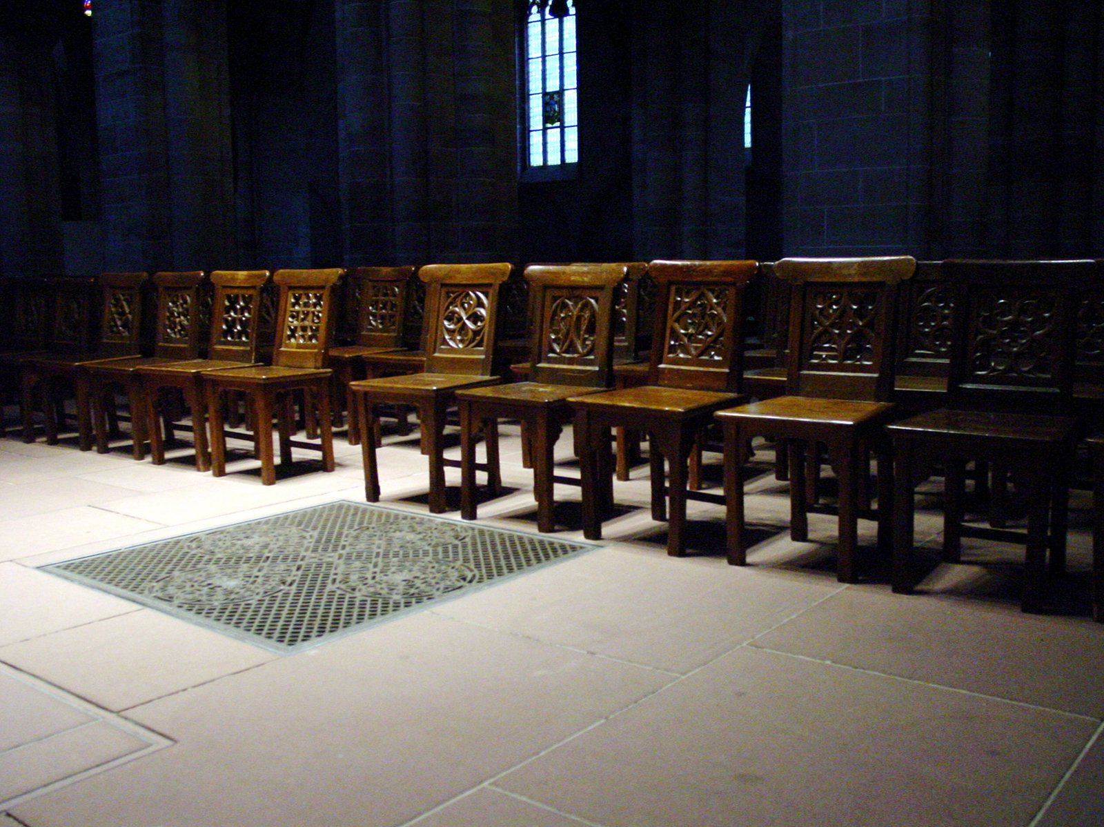 a row of wooden chairs lined up in front of a rug