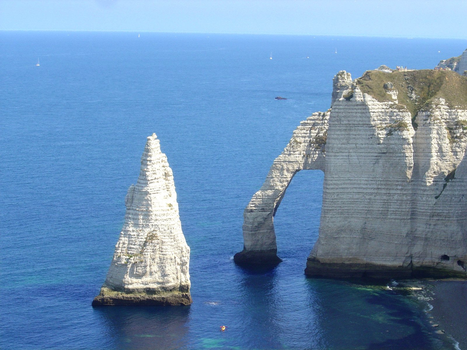 two tall rocks are floating in the blue ocean