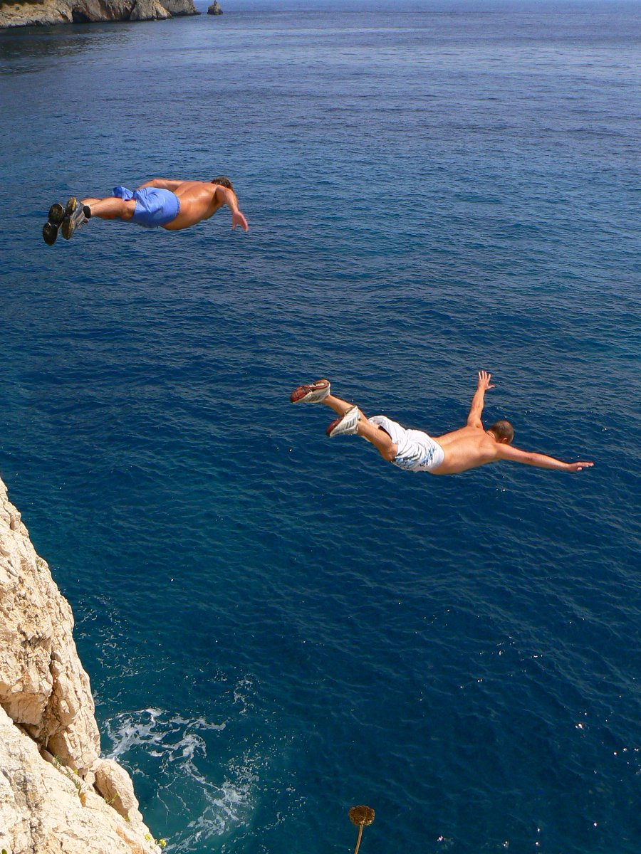 two men diving in the ocean in swimsuits