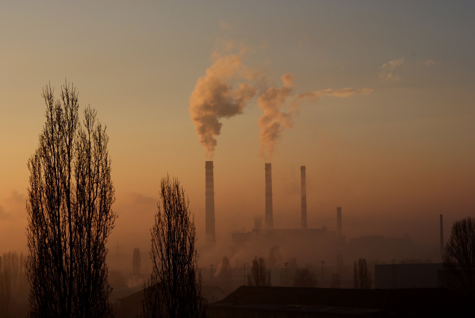 the smoke stacks out of factory chimneys, as the sun rises