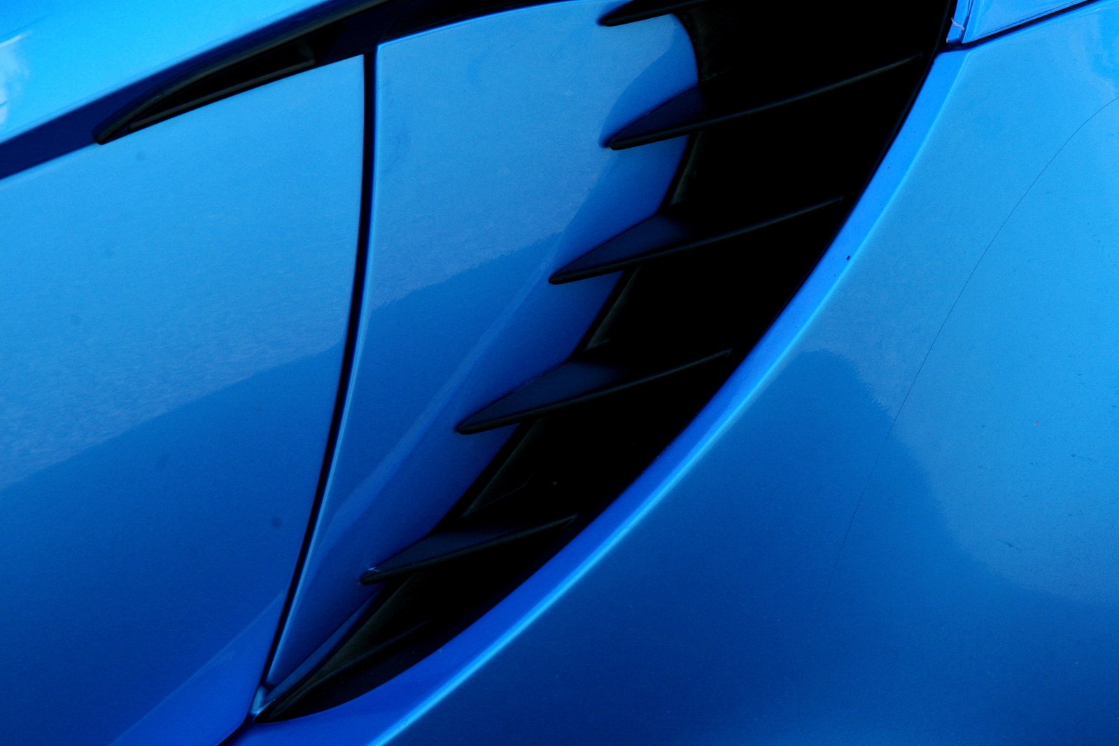 a close up image of the hood of a blue sports car