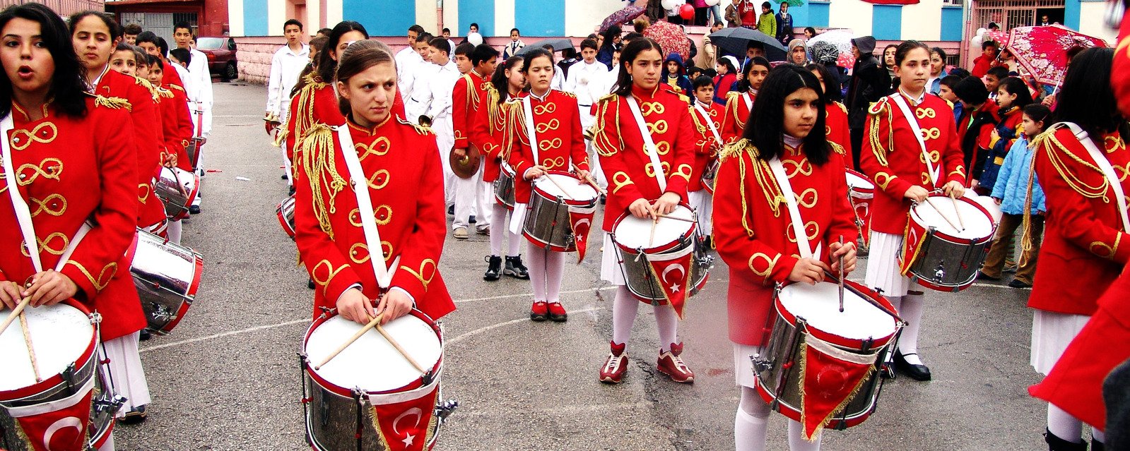 a group of people dressed in red marching uniforms marching down a street