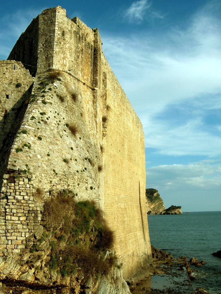 an old stone wall sitting on top of the ocean