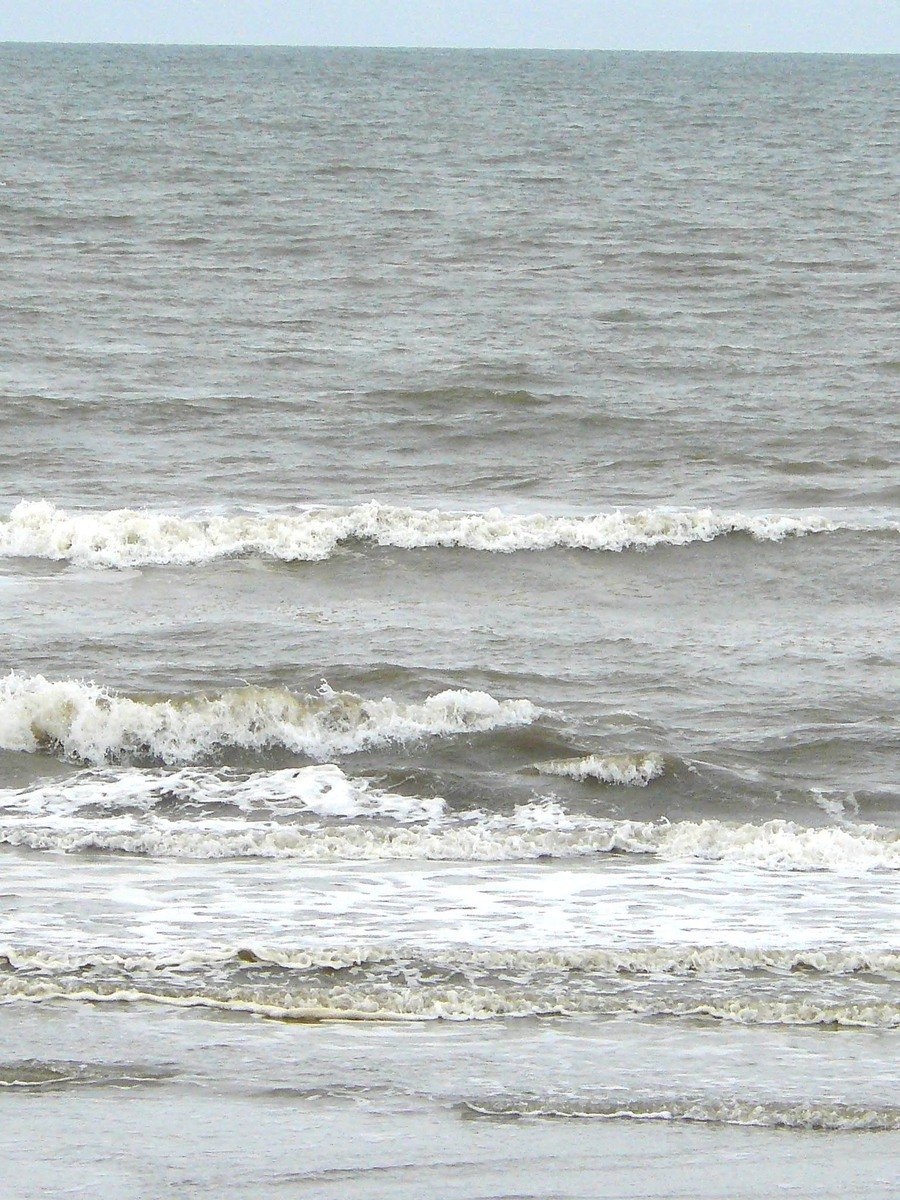 a man is walking along the beach with surfboards