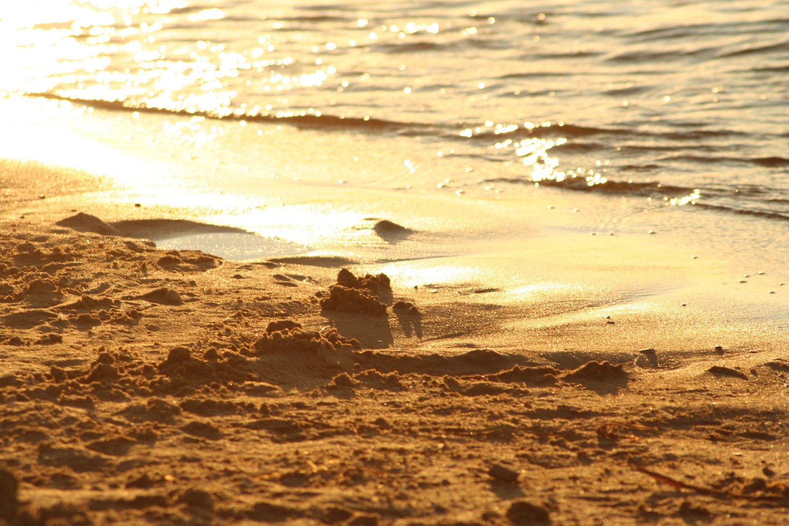 a sandy beach next to the ocean with a small sandcastle