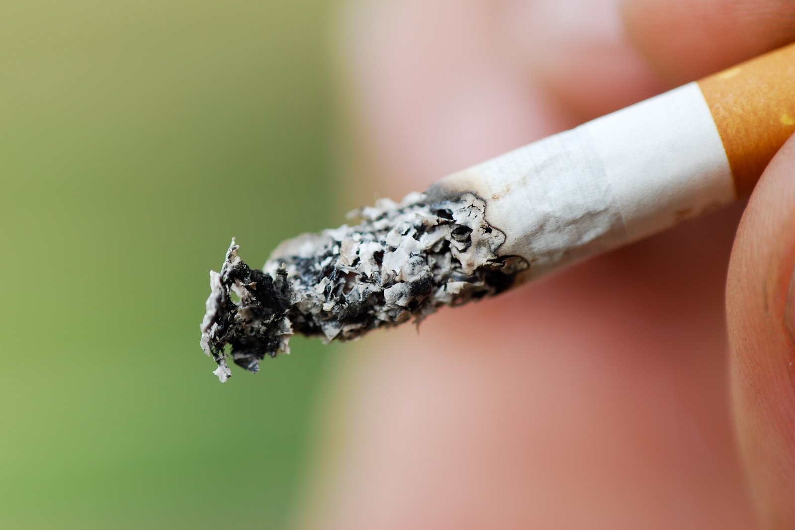 a person holding a cigarette with smoke on it