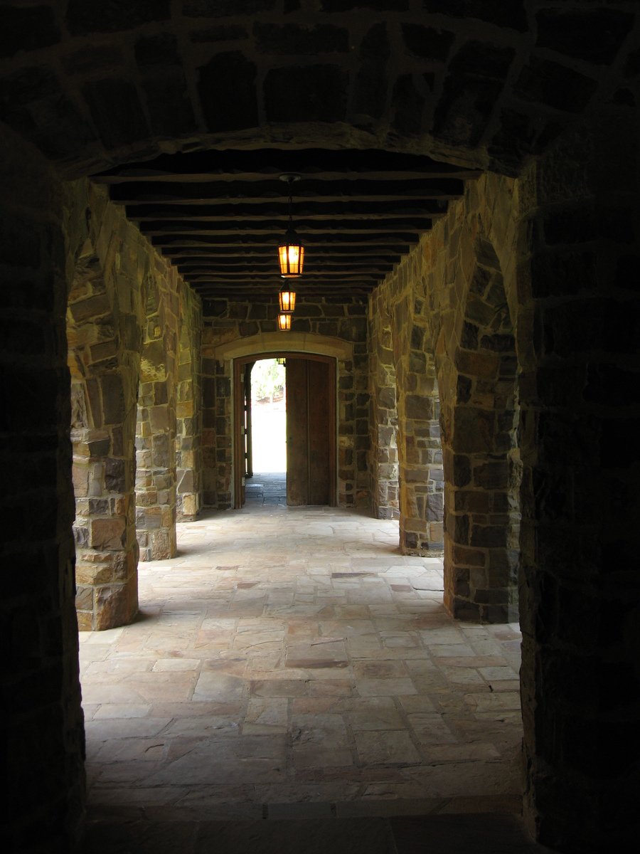 dark arched corridor with lights at end and light bulb on each side