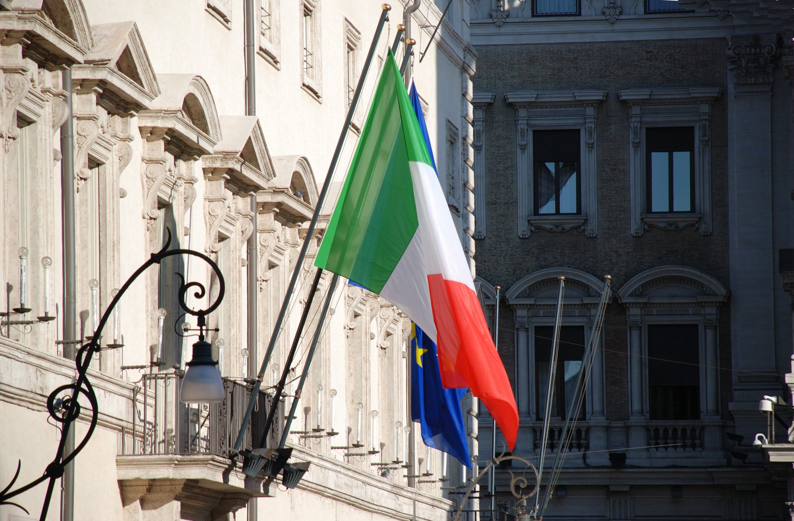 two flags are seen near many buildings on a street