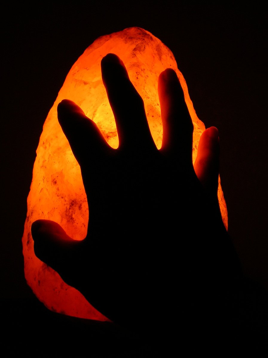 a hand holds an illuminated, dim, orange light