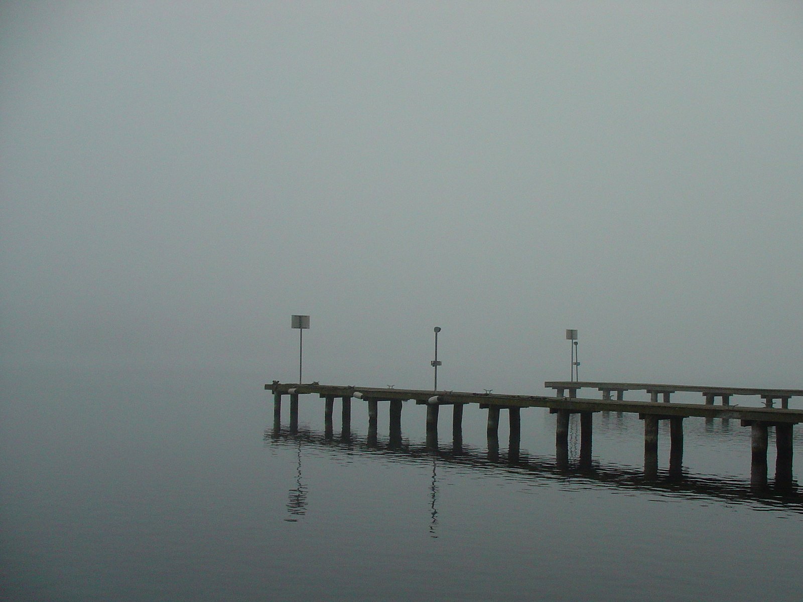 the pier sits in the fog at the water's edge