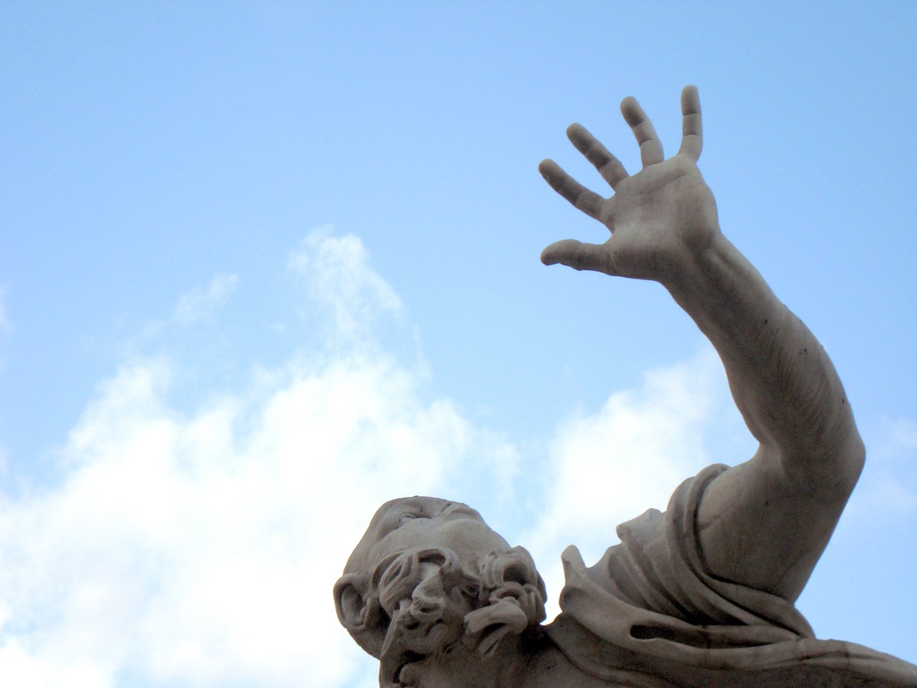there is a statue of a person reaching up into the sky