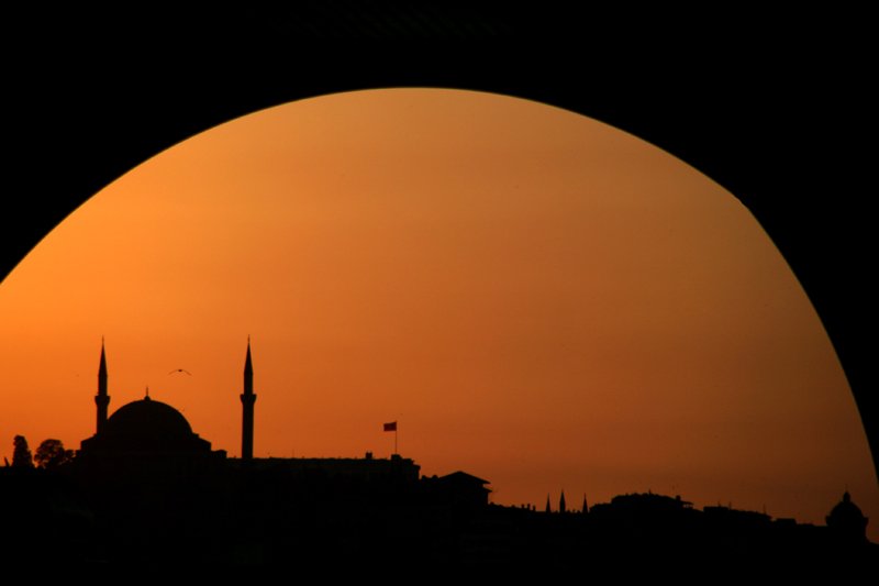 an arch shows the silhouette of a mosque in the distance