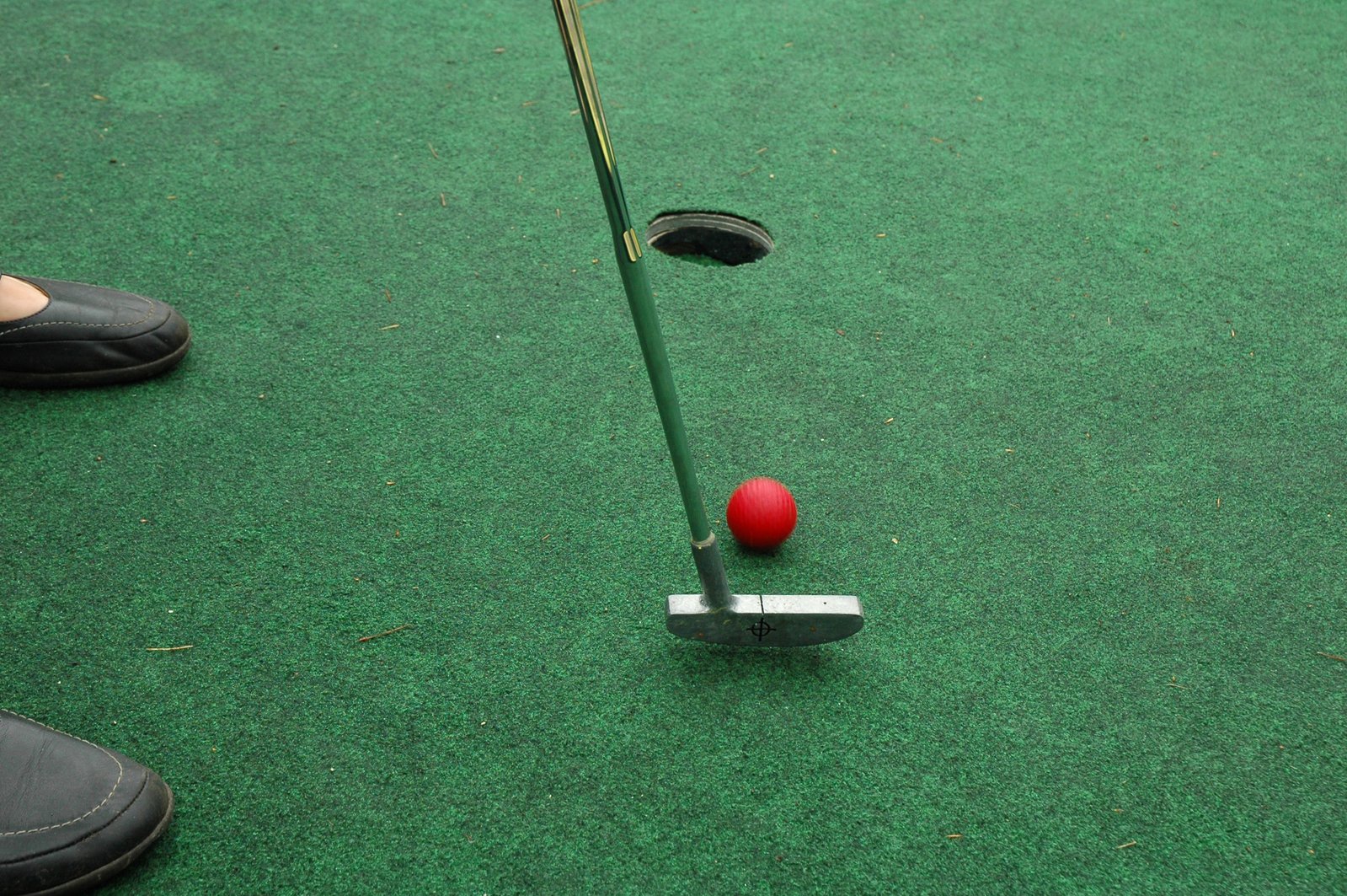 the red ball is sitting on a green golf course