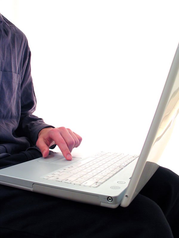 a man is sitting and typing on his laptop