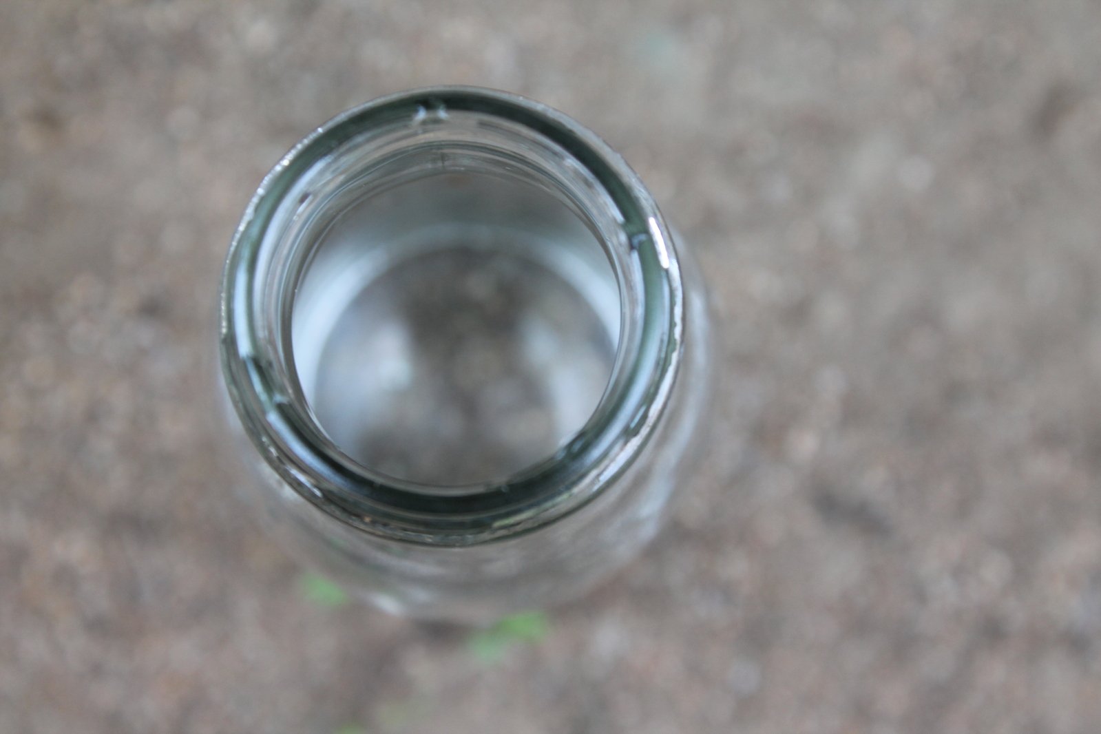 a glass bottle with a lid that is sitting on the ground