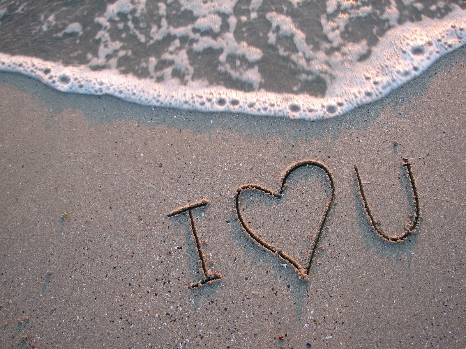 the word i love you written in sand on the beach