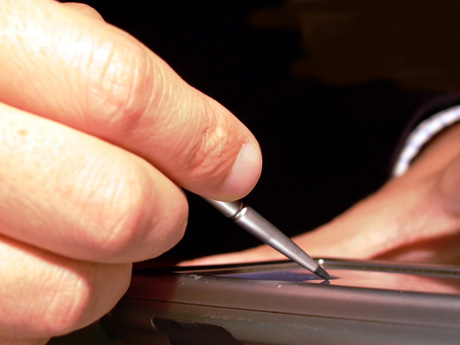 a hand is holding a pen in the process of removing a screen from a laptop