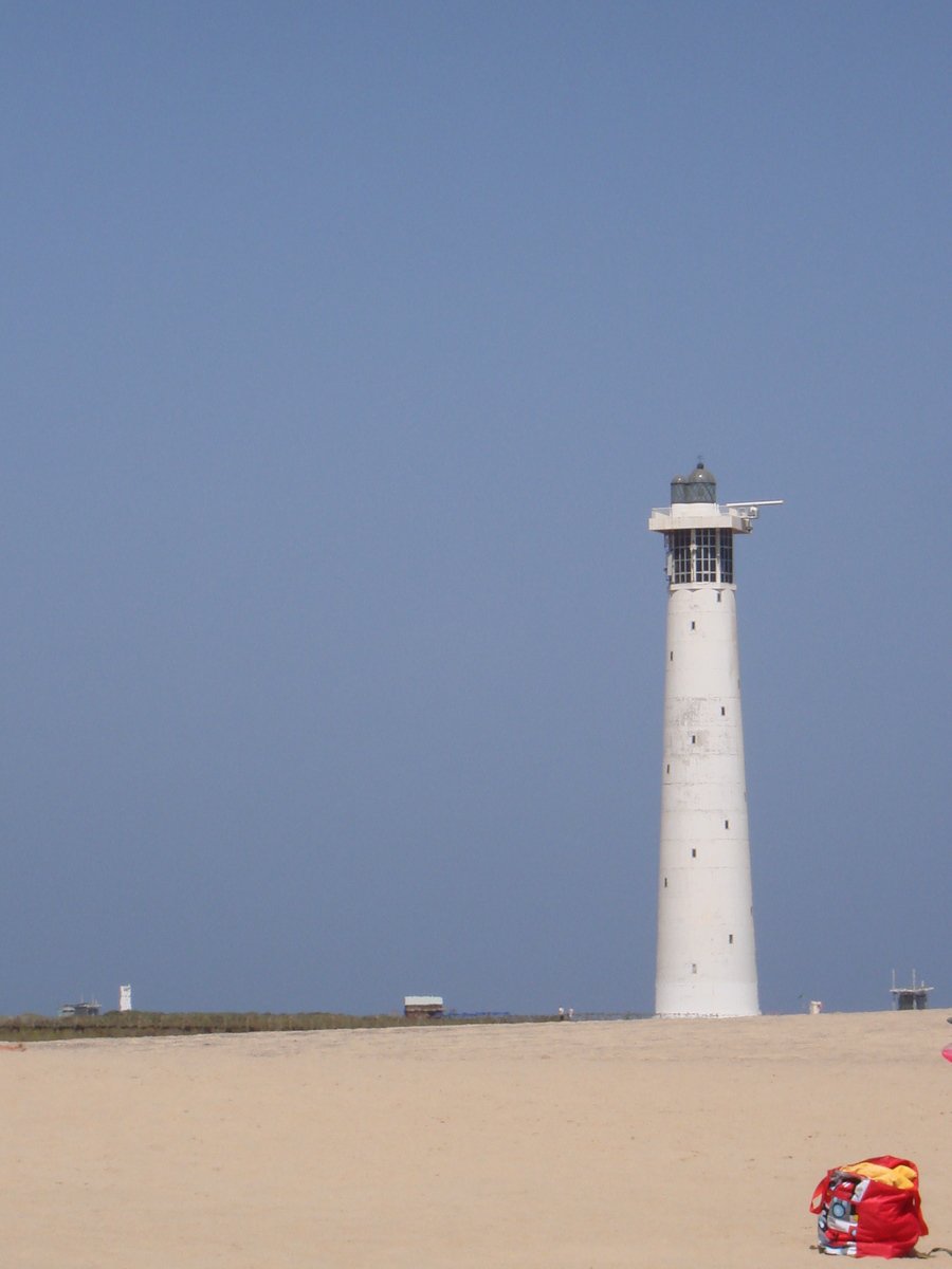 a light tower near a beach in the sand