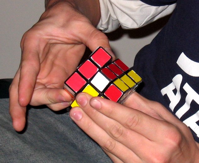 a man's hands with one hand grabbing a rubik cube