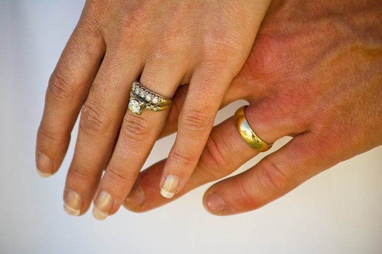 a couple holds their wedding ring in each hand