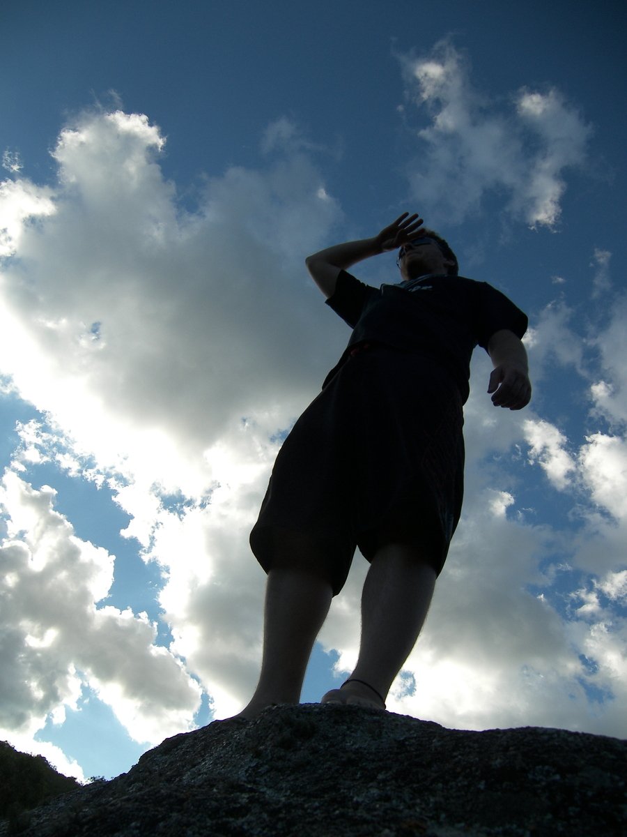 a man standing on top of a cliff looking up at the sky