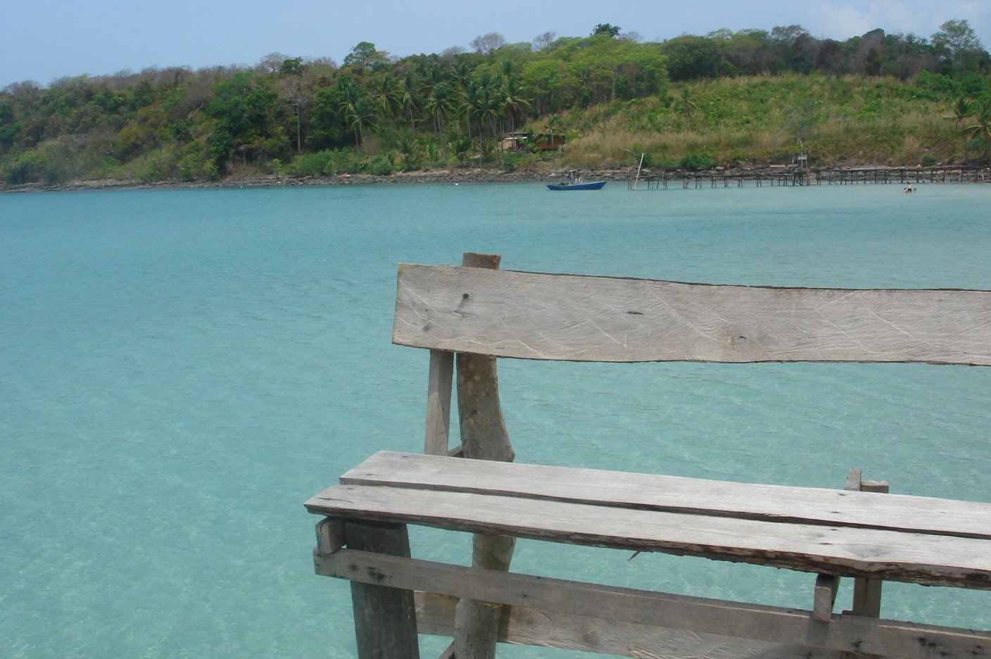 a wooden bench sits by the ocean water
