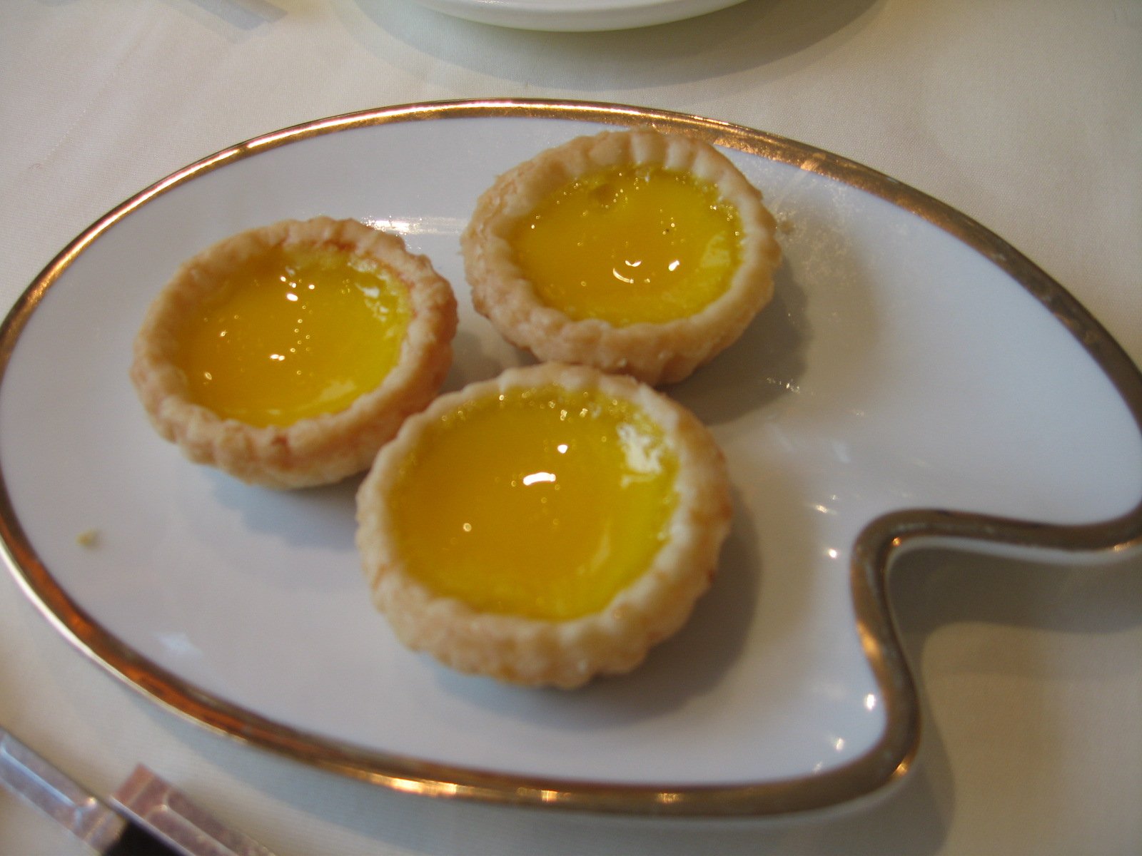 three lemon pies sit on a white and gold plate