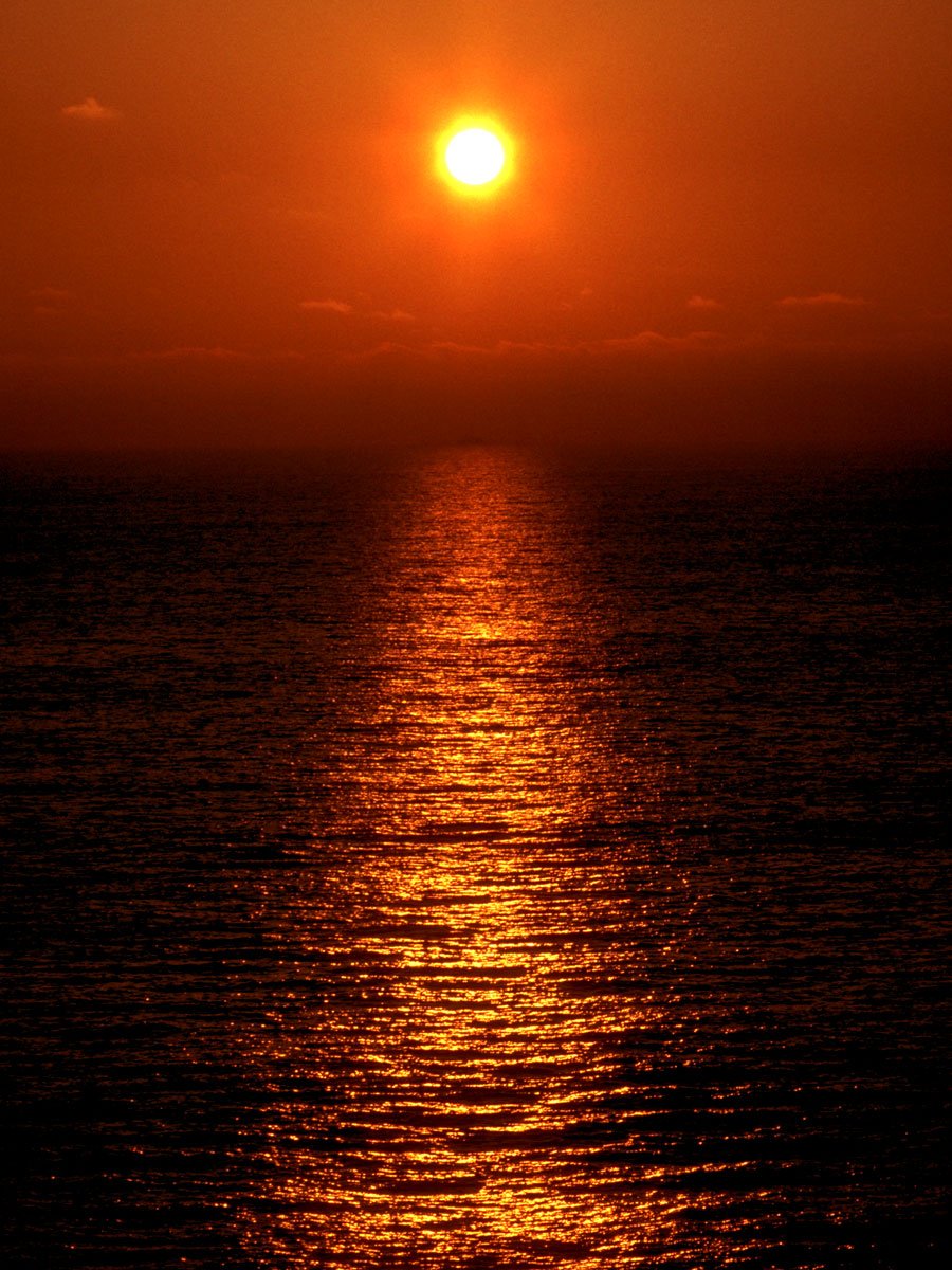 the sun is setting over a calm ocean
