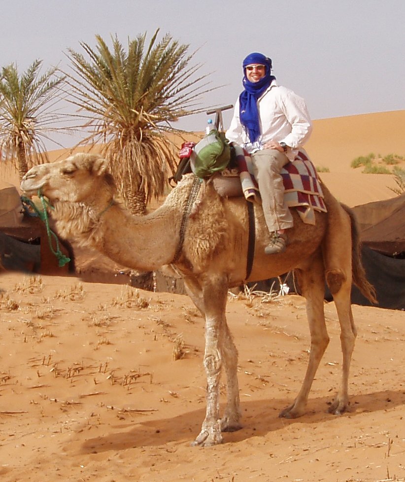 the man is riding his camel in the desert