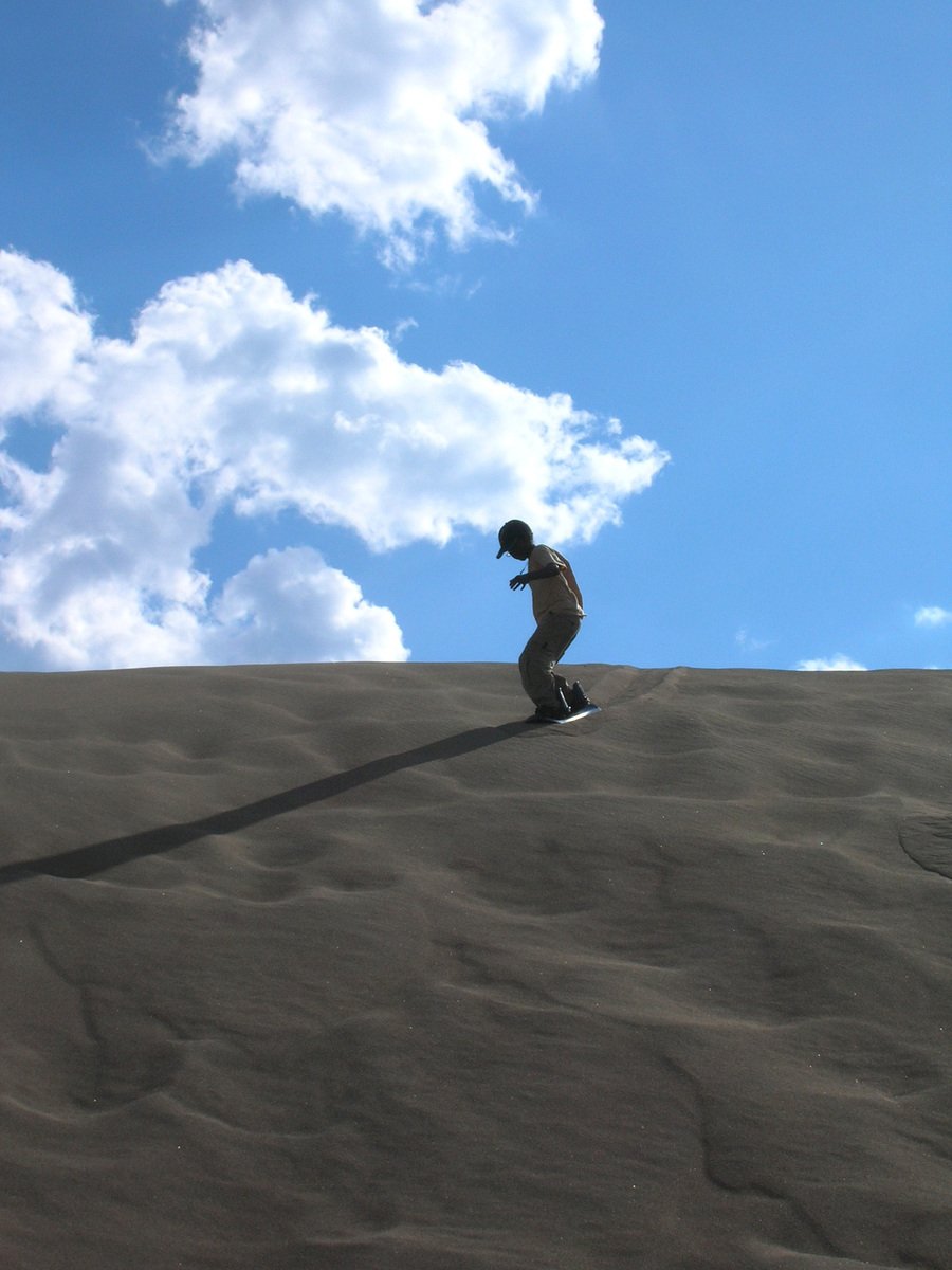 a man riding a snowboard on top of a sand hill