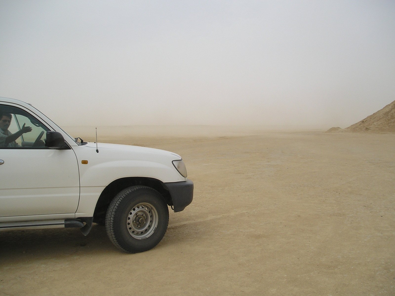 the white pickup truck sits near several piles of sand