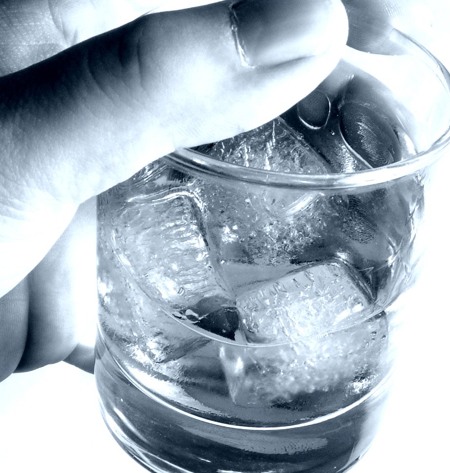 someone is grabbing the ice cubes in a glass