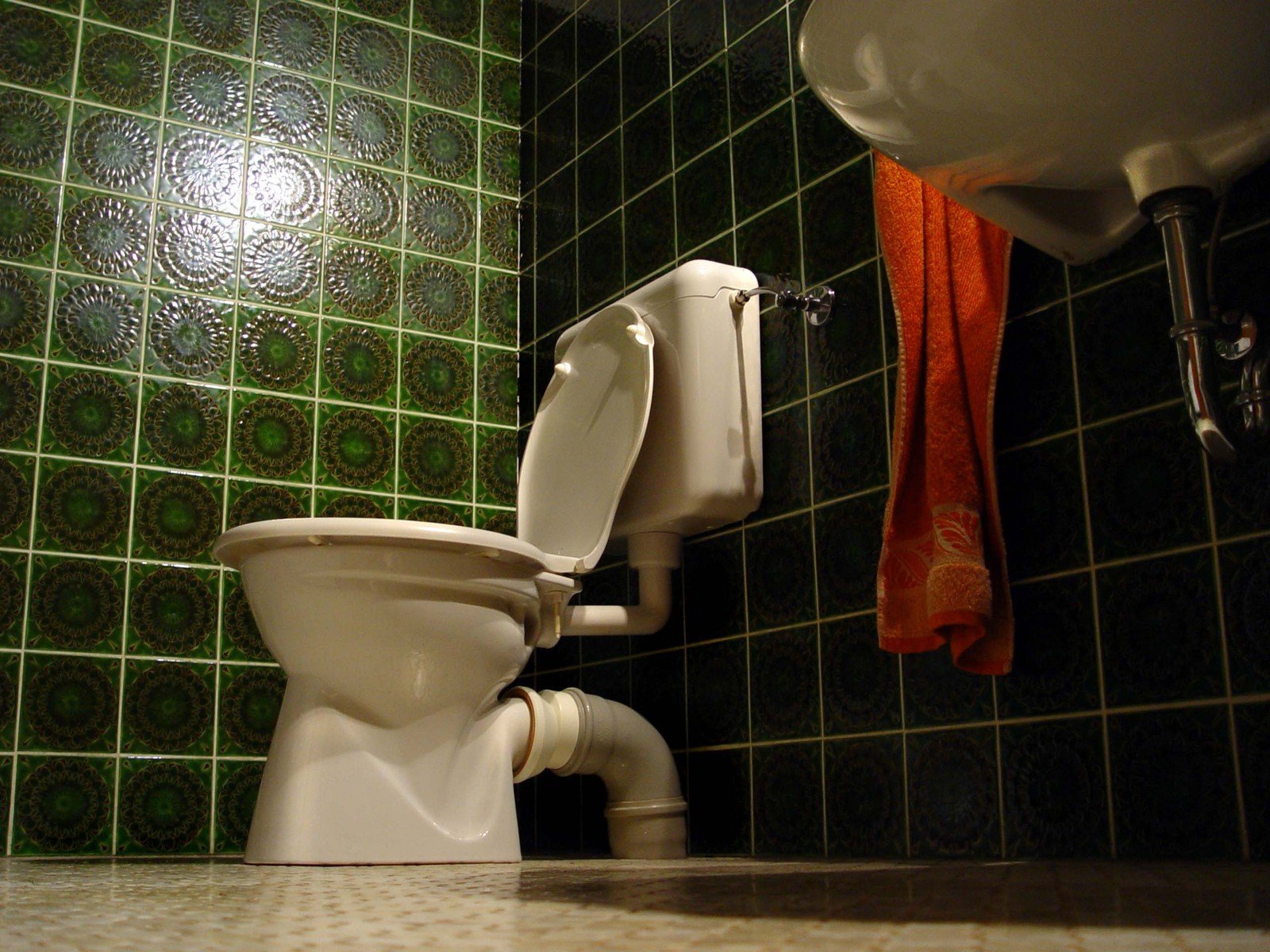 a clean white toilet in front of green tile